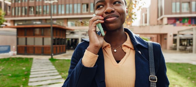 Female african student talking on the phone near the university campus