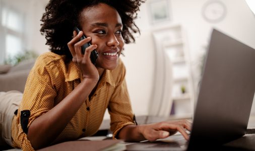 Student studying at home, working with her laptop computer and having phone call.